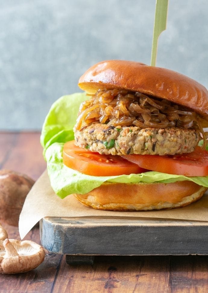 vegan mushroom burger topped with caramelized onions, tomatoes and lettuce.