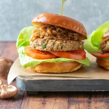 vegan mushroom burger topped with caramelized onions, tomatoes and lettuce.