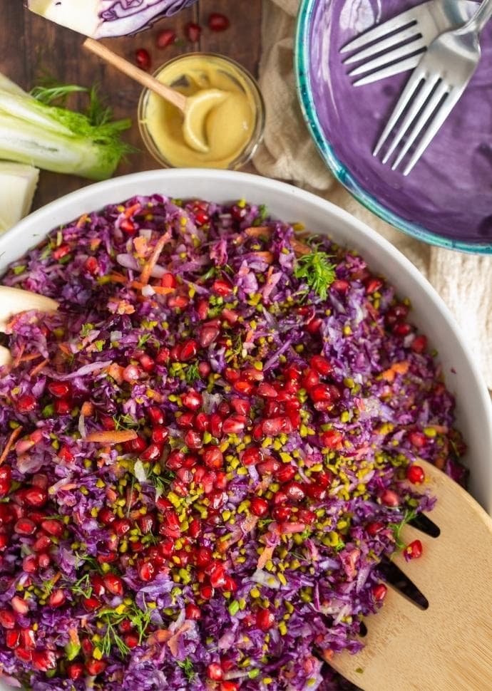 winter slaw topped with pomegranate seeds and pistachio nuts.