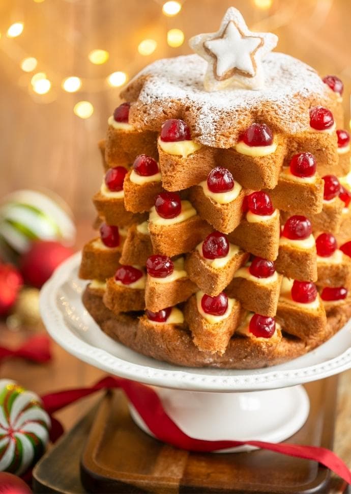 Pandoro Christmas tree cake filled with pastry cream and topped with candied cherries.