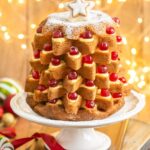 Pandoro Christmas tree cake filled with pastry cream and topped with candied cherries.