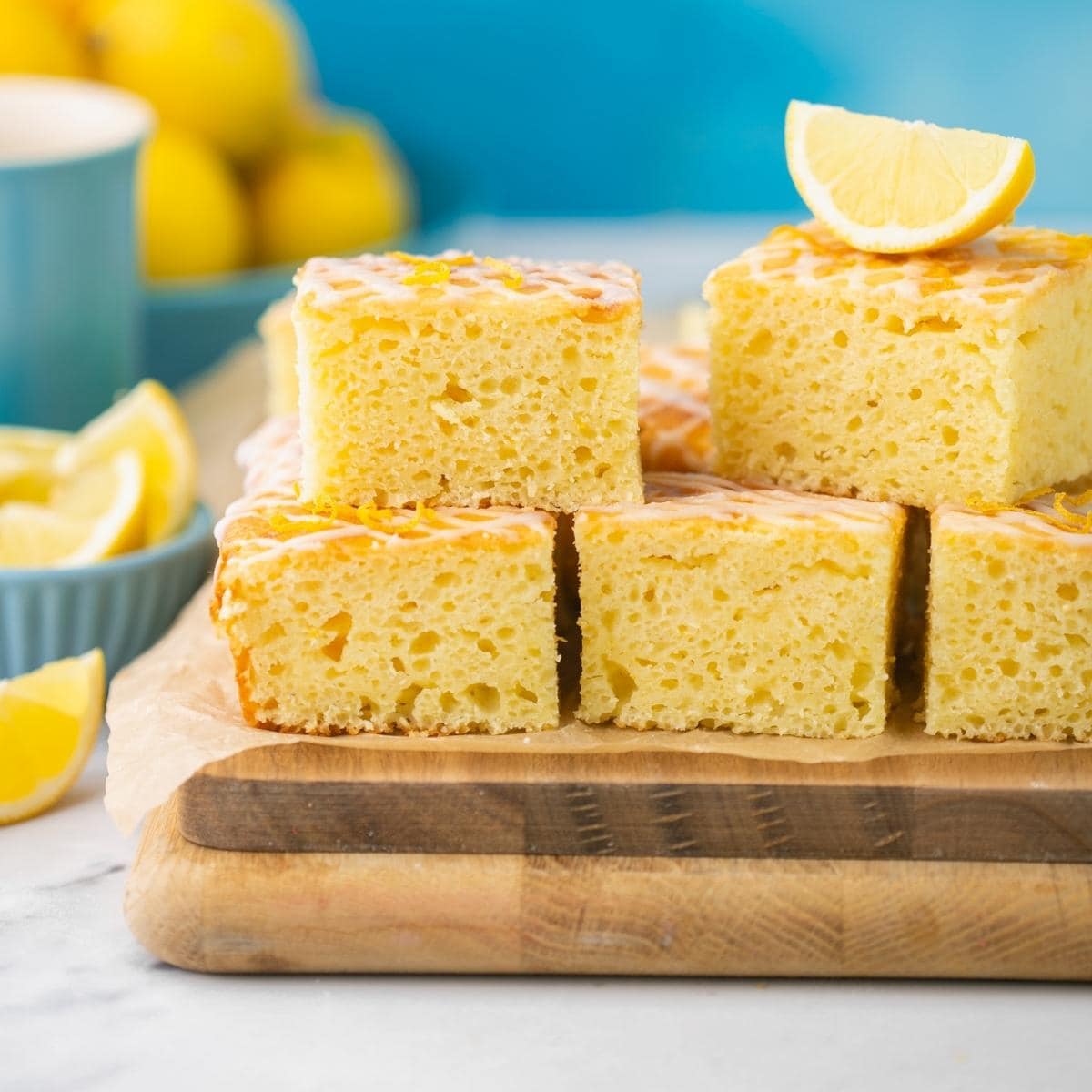 lemon ricotta cake cut into square slices drizzled with lemon glaze over the top.
