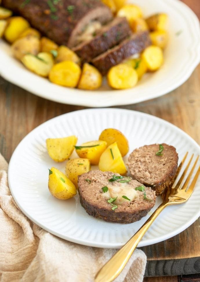 italian meatloaf stuffed with cheese sliced and served with roasted potatoes.