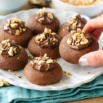 nutella thumbprint cookies topped with hazelnuts.