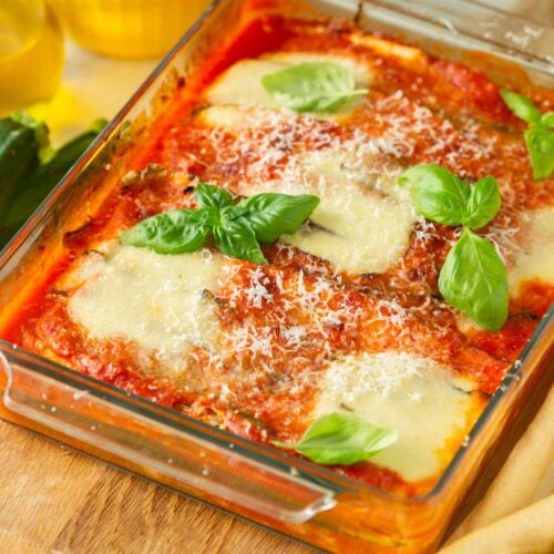zucchini parmigiana served hot with mozzarella cheese, parmesan cheese and basil on top.