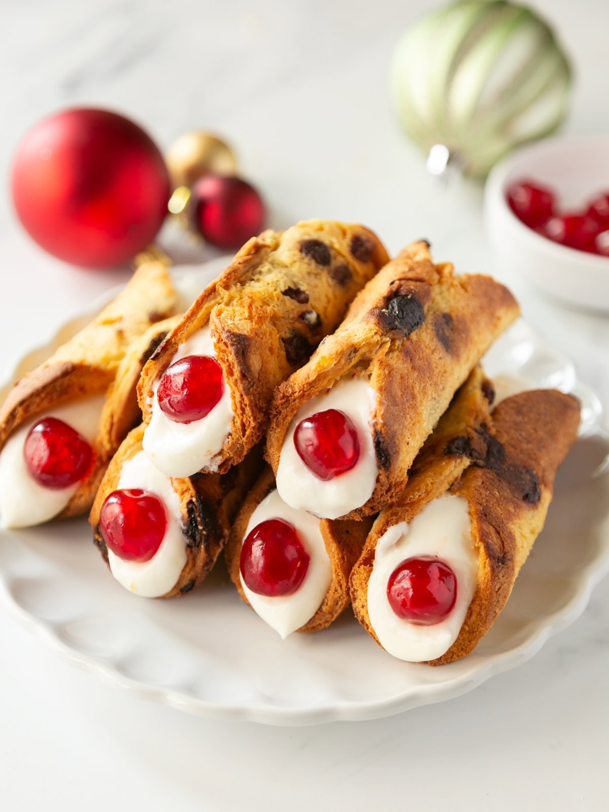 christmas cannoli made with panettone shells, ricotta filling and decorated with candied fruit.