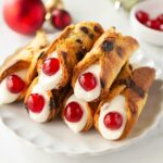 christmas cannoli with panettone shells, filled with ricotta cream and decorated with candied cherries.