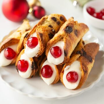 christmas cannoli with panettone shells, filled with ricotta cream and decorated with candied cherries.