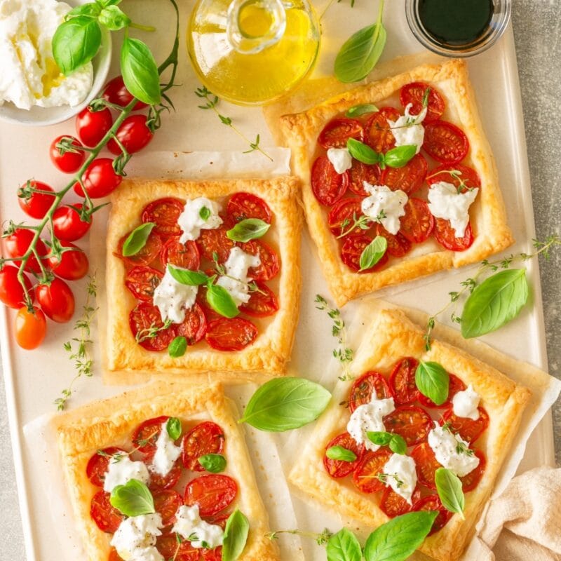 Easy starter recipes featuring tomato and ricotta puff pastry tarts with fresh basil.