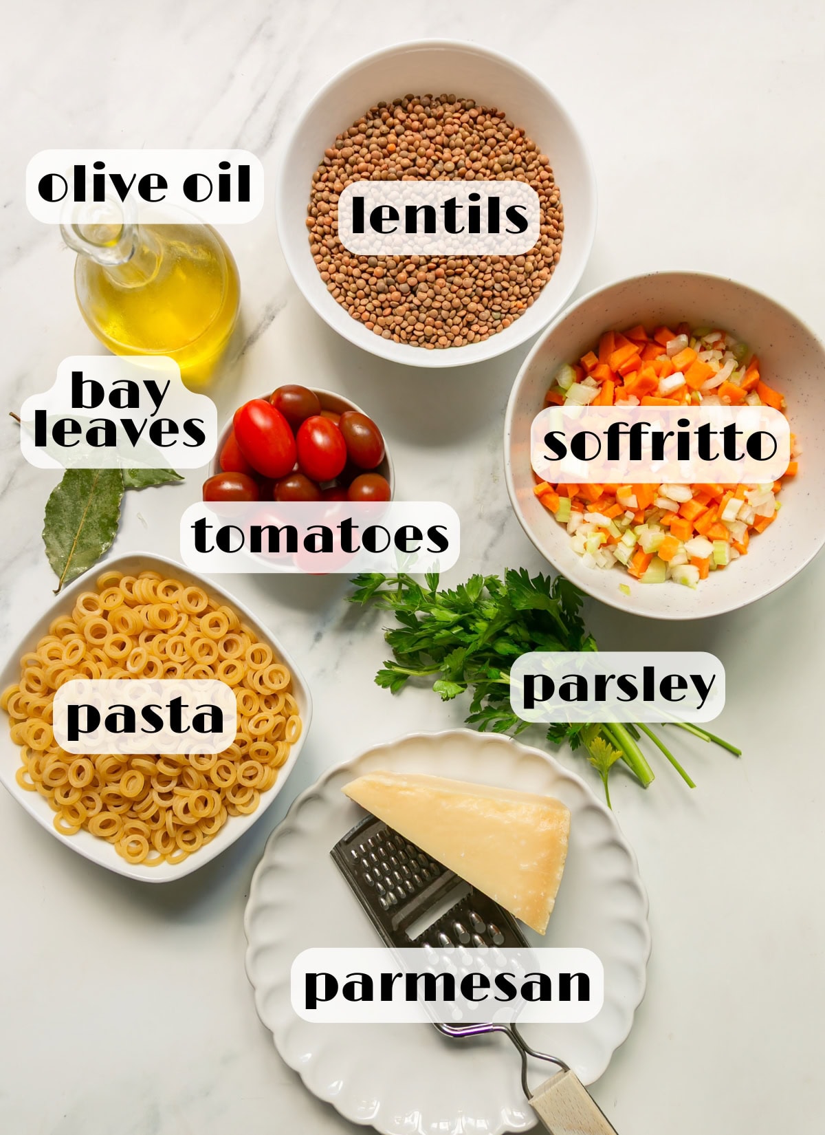 italian lentil soup ingredients: lentils, pasta, bay leaves, parmesan, olive oil, soffritto, tomatoes, parsley.
